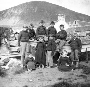 A group of boys pictured in the Village on Hirta with the manse and kirk in the backround.