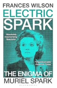 Image of a book cover featuring a monochrome teal‑tinted photograph of a woman occupies most of the cover, framed within a halftone dot pattern. The woman's gaze is directed slightly upward. The title “ELECTRIC SPARK” appears in bold uppercase letters across the top, with the author’s name “FRANCES WILSON” above it in black. Below the photograph, the subtitle “THE ENIGMA OF MURIEL SPARK” is printed in large white uppercase text.