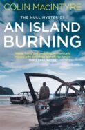 Image of a book cover featuring a coastal scene under an overcast sky with blue‑grey clouds. In the foreground, the rusted remains of a burned‑out car sit in the sand, with large holes in the metal and peeling paint. A second damaged car is visible farther back on the beach. Near that car, a solitary human figure sits on the open frame, facing toward the sea. The title ‘AN ISLAND BURNING’ appears in large white uppercase letters across the upper middle of the cover, with the subtitle ‘THE MULL MYSTERIES’ in smaller text above it. The author’s name, ‘COLIN MACINTYRE,’ is printed at the top in yellow uppercase letters.