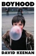 Image of a book cover featuring a photograph of a young brown haired boy outdoors, centred against a blurred urban background. The boy is blowing a large, nearly translucent pink bubble of chewing gum that obscures much of their face. He wears a brown jacket with a zip. The image is framed by a thick white border. The title “BOYHOOD” appears in bold black uppercase letters at the top of the border, and the author’s name “DAVID KEENAN” appears in matching black text at the bottom.