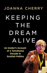 Image of a book cover featuring a black background with bold white uppercase text reading “KEEPING THE DREAM ALIVE.” in the middle of the image. Above the title, the author’s name “JOANNA CHERRY” appears in yellow. Below the title, the subtitle “An Insider’s Account of a Tumultuous Decade in Scottish Politics” is printed in yellow. In the lower right quadrant of the image, there is a photograph image of a woman with short blonde hair, wearing glasses and standing at a podium, giving a speech. She is dressed in a brown jacket and has a yellow lanyard around her neck.
